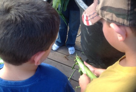 George explaining to Charlie how to shuck the corn.
